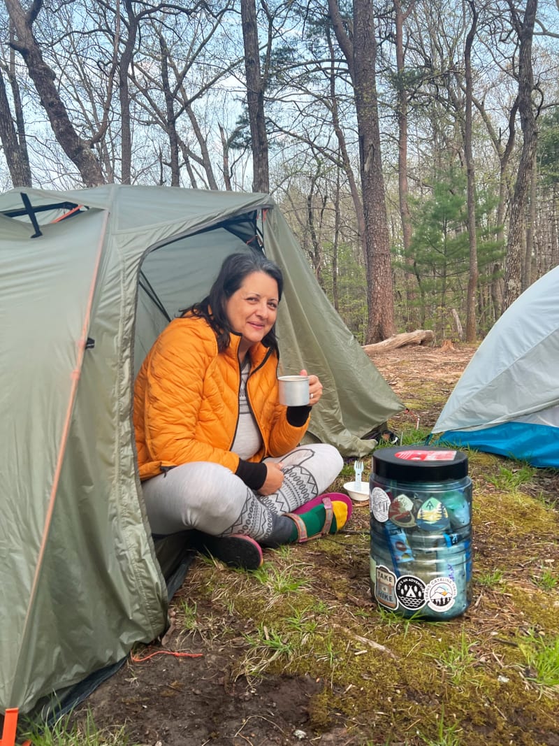A woman smiling and sitting at the door of her tent while hiking in Georiga.