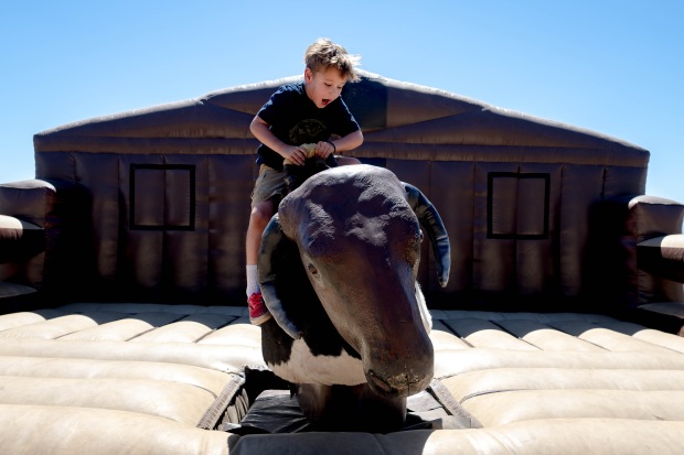 Frankie Van Cleave, 6, rides a mechanical bull during...